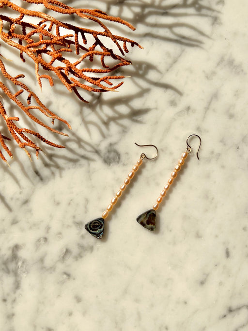 Drop earrings with rice pearls & abalone triangles.   Materials Matter: pink rice pearls & farm raised abalone beads on gold fill ear wires.  Made by Badass Women for Badass People: Designed in California by Carrie Marill and made by hand in her SoCal studio.   