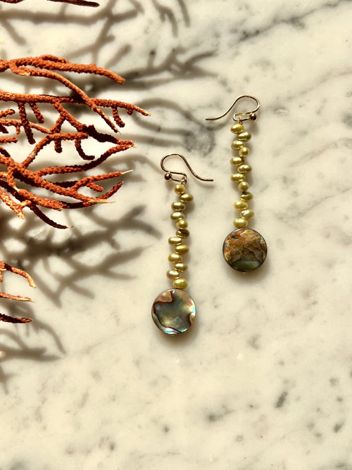 Drop earrings of stacked green pearls with complimentary abalone disks.   Materials Matter: green rice pearls with blue green farmed abalone disks on gold fill ear wires.   Made by Badass Women for Badass People: Designed in California by Carrie Marill and made by hand in her SoCal studio.