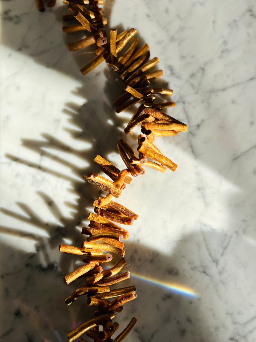 Embellish your space with a golden coral window prism - hang in a sunny spot & watch the rainbows dance! Chunky coral beads with a gold finish, beaded on sturdy wire, faceted prism.  Coral - an amulet from the sea, provides protection over the feminine & our emotional waters.