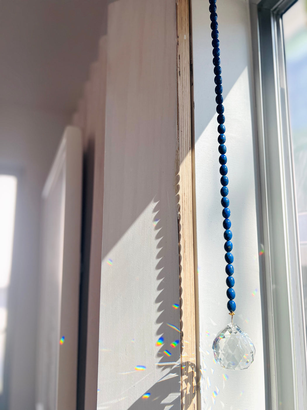 Lapis Lazuli window prism transforms any space into a zen den - hang in a sunny spot & watch the rainbows dance!  Third eye activating Lapis Lazuli clears out the BS so you can benefit the most from your meditations. Designed in California by Carrie Marill and made by hand in her SoCal studio.